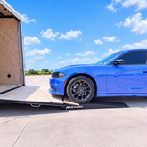 Blue car driving up MaxRamps Car Hauler Ramps and entering an enclosed car trailer. 