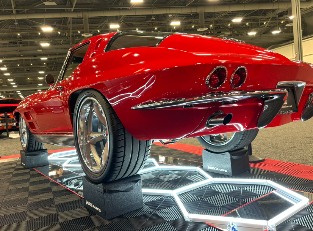 Red classic Corvette on MaxRamps wheel cradles on a show display floor.