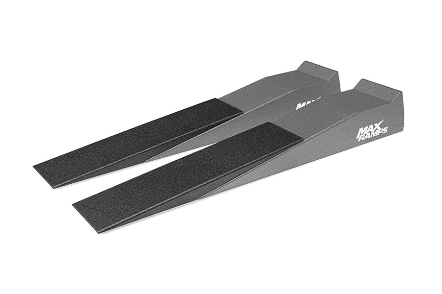 A pair of black textured MAX RAMPS ramp extenders, shown at an angle on a plain white background overlayed on a semi-transparent image of a pair of ramps to demonstrate the use of the ramp extenders